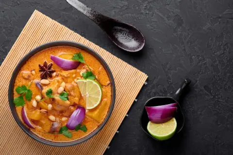 Aksamitna, żółta pasta curry z kurczakiem, orzeszkami ziemnymi, limonką i czerwoną cebulą.