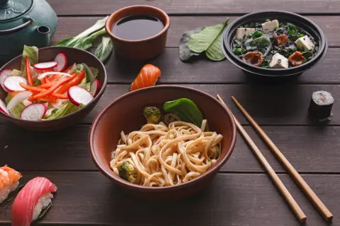 Sos sojowy do czego? Do makaronu, sushi i zupy. Pyszne azjatyckie dania na drewnianym stole.