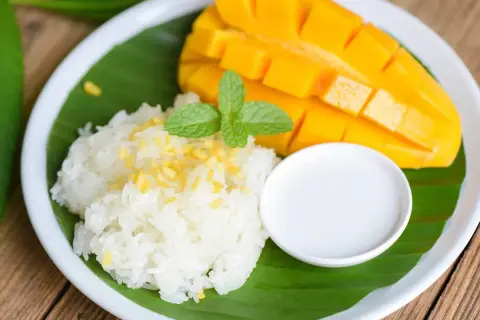 Słodki ryż z mango, udekorowany miętą i polany mleczkiem kokosowym. Pyszny deser, który przeniesie Cię w tropikalne rejony.
