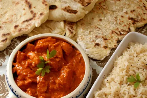 Pyszny butter chicken z chlebkiem naan i ryżem. Idealny posiłek dla miłośników indyjskich smaków.