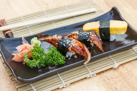 Sushi z węgorzem w sosie unagi. Co to za pyszny sos? Na talerzu też tamago, wasabi i marynowany imbir.