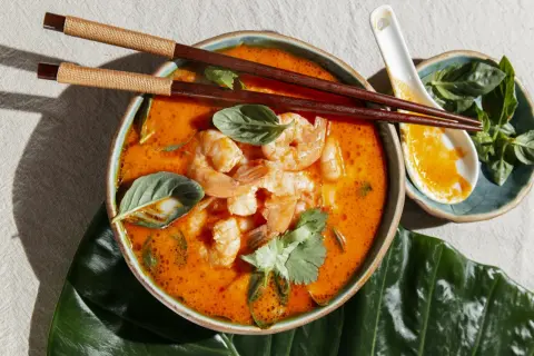Aksamitny, pomarańczowy bulion z krewetkami i ziołami, idealny do jedzenia pałeczkami. To pyszne danie to klasyczne **pasta tom yum**.