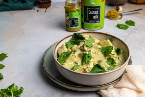 Miseczka kremowego curry z kurczakiem i szpinakiem, przygotowanego z zielonej pasty curry i mleczka kokosowego.