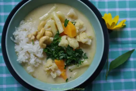 Aksamitny kremowy sos z ryżem, kalafiorem, orzechami nerkowca i marchewką. Pyszne danie inspirowane smakami tajskiej kuchni, przypominające **pasta tom kha**.
