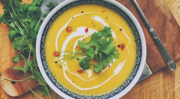 Aksamitna zupa dyniowa z mlekiem kokosowym, udekorowana świeżą kolendrą i chili. Idealna na chłodne dni.