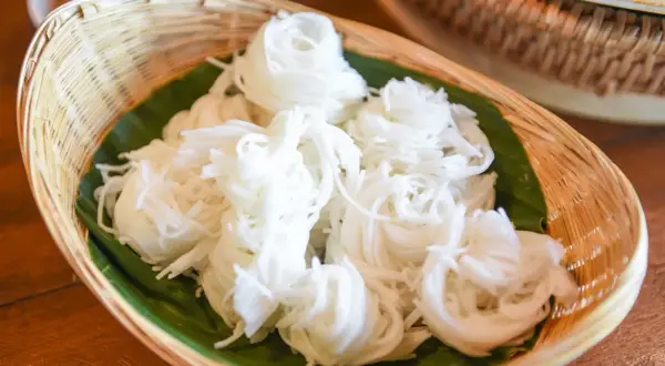 Biały makaron ryżowy w wiklinowym koszyku, podany na liściu bananowca. Czy makaron ryżowy ma gluten? Nie, jest bezglutenowy!
