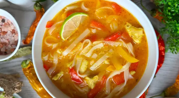 Aromatyczna zupa z makaronem ryżowym, z kawałkami kurczaka, papryki i plasterkiem limonki.