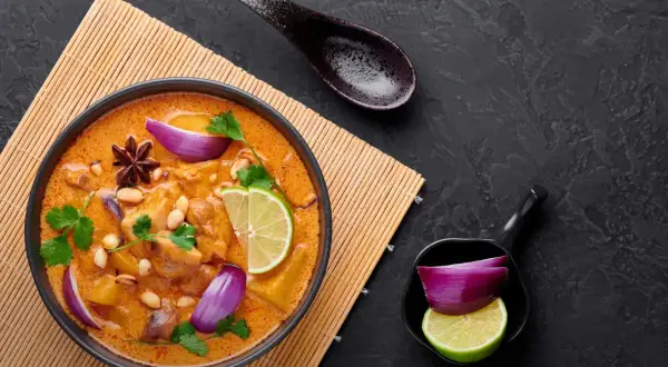 Aksamitna, żółta pasta curry z kurczakiem, orzeszkami ziemnymi, limonką i czerwoną cebulą.