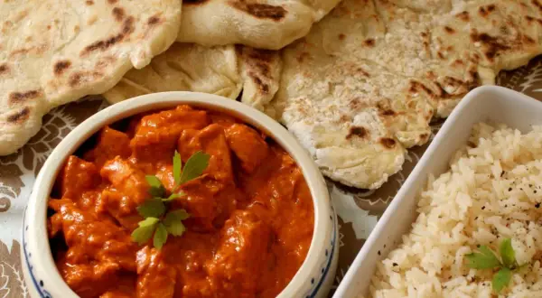 Pyszny butter chicken z chlebkiem naan i ryżem. Idealny posiłek dla miłośników indyjskich smaków.
