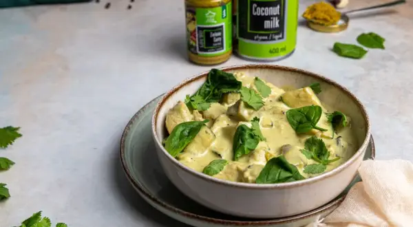Miseczka kremowego curry z kurczakiem i szpinakiem, przygotowanego z zielonej pasty curry i mleczka kokosowego.