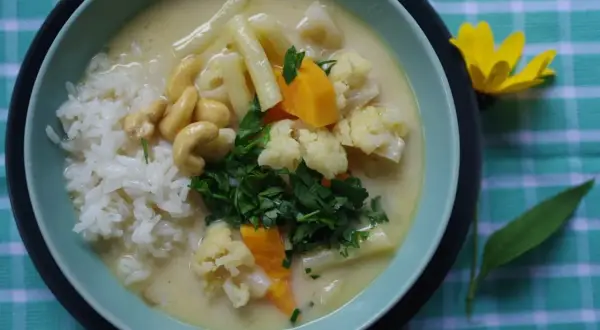 Aksamitny kremowy sos z ryżem, kalafiorem, orzechami nerkowca i marchewką. Pyszne danie inspirowane smakami tajskiej kuchni, przypominające **pasta tom kha**.