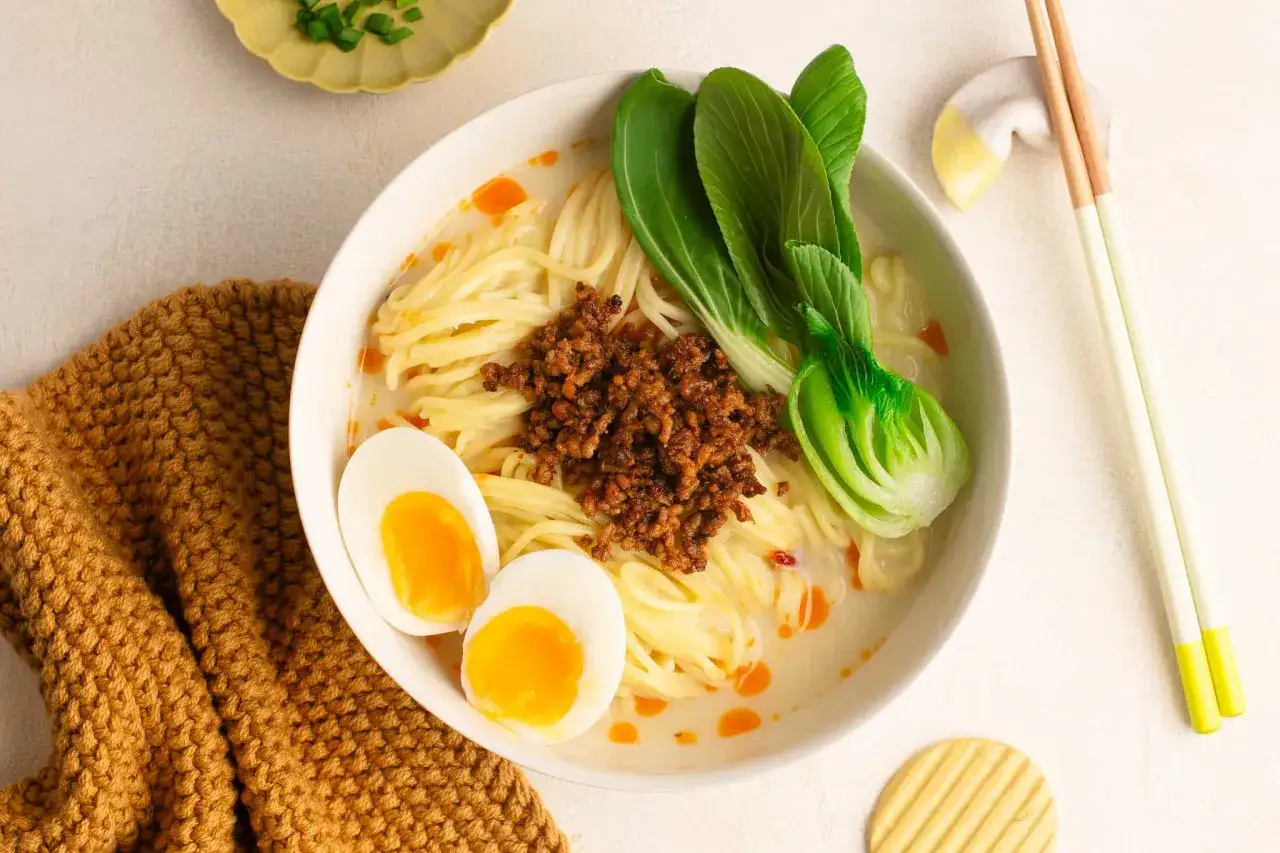 Miseczka aromatycznego tan tan ramen z mielonym mięsem, jajkiem na pół i pak choi.