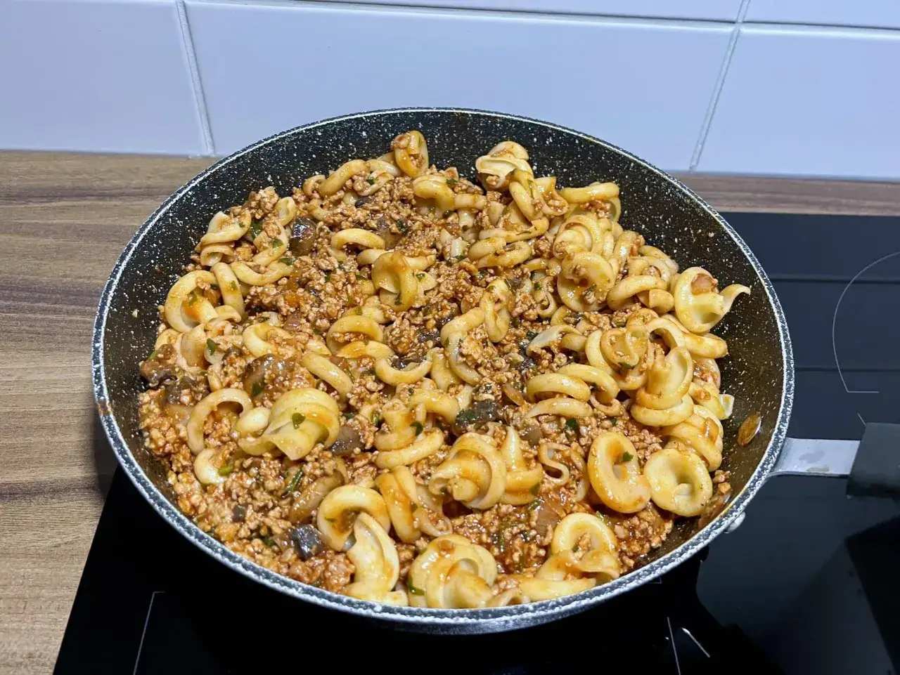 Pyszny makaron z wieprzowiną i grzybami w sosie, gotowy do podania prosto z patelni.